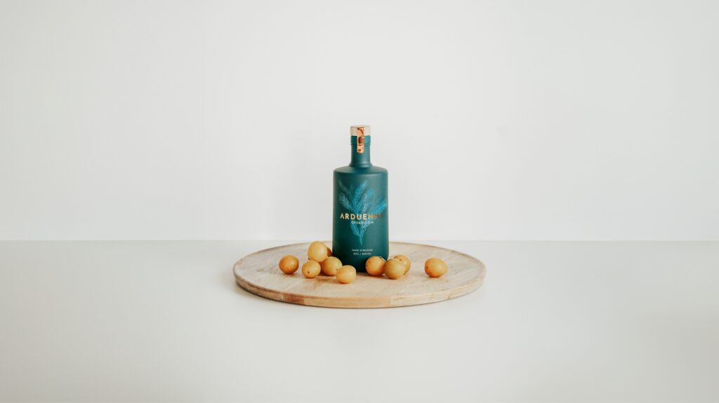 Arduenna Organic Gin auf einem Holzbrett mit Mirabellen