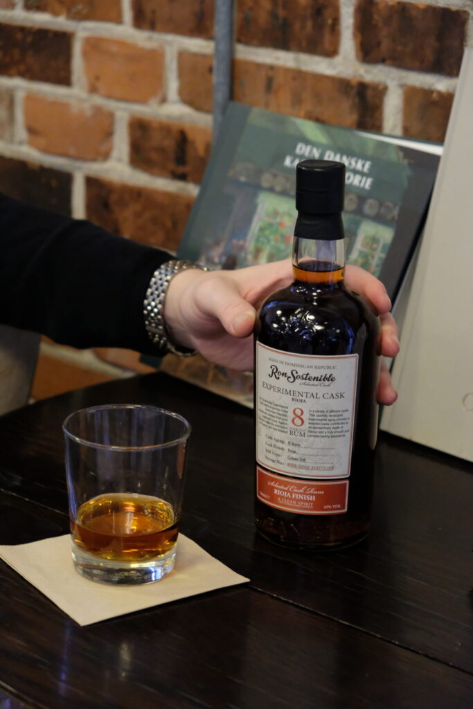 Ron Sostenible 8 Jahre Experimental Cask Rioja in der Hand, Glas daneben