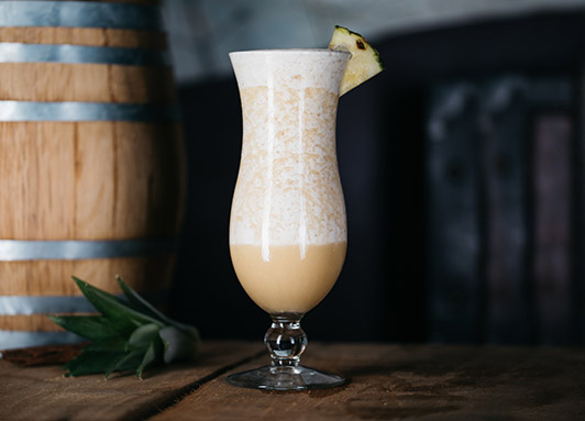 Escape Cocktail im Hurricane-Glas mit Ananas und Zimt