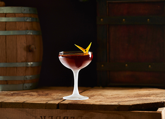 Gerührter Rum-Cocktail im Coupette-Glas mit Orangenzeste